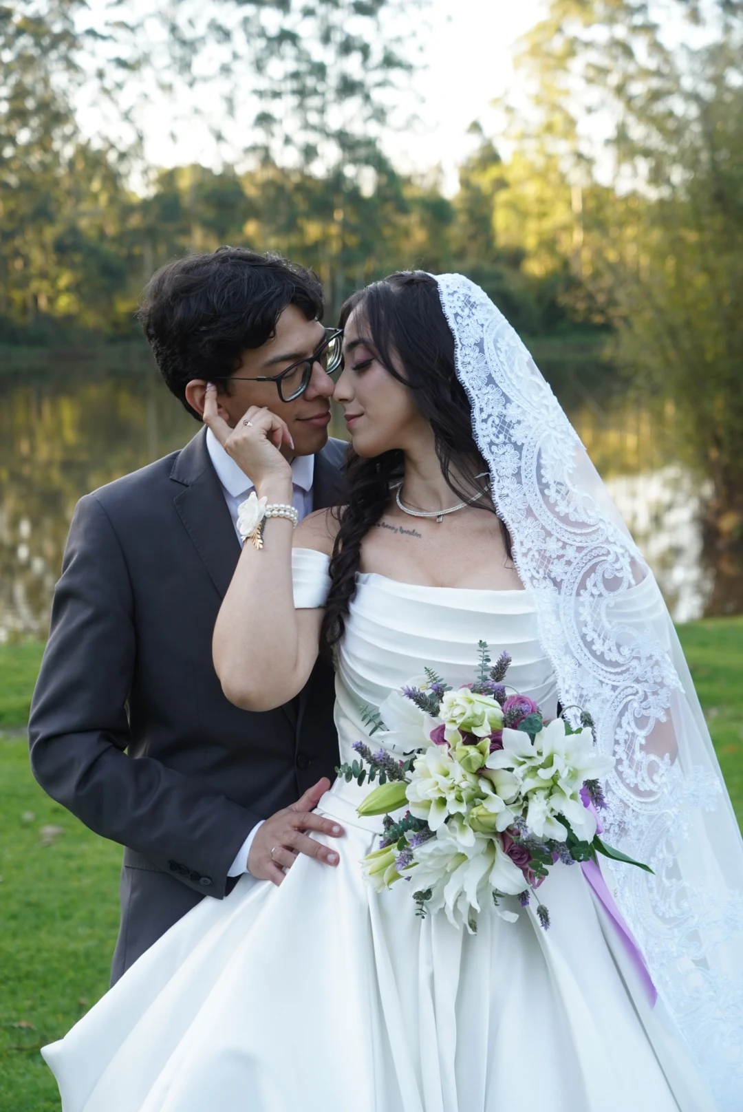 Casal de noivos junto a um jardim, com buquê de flores