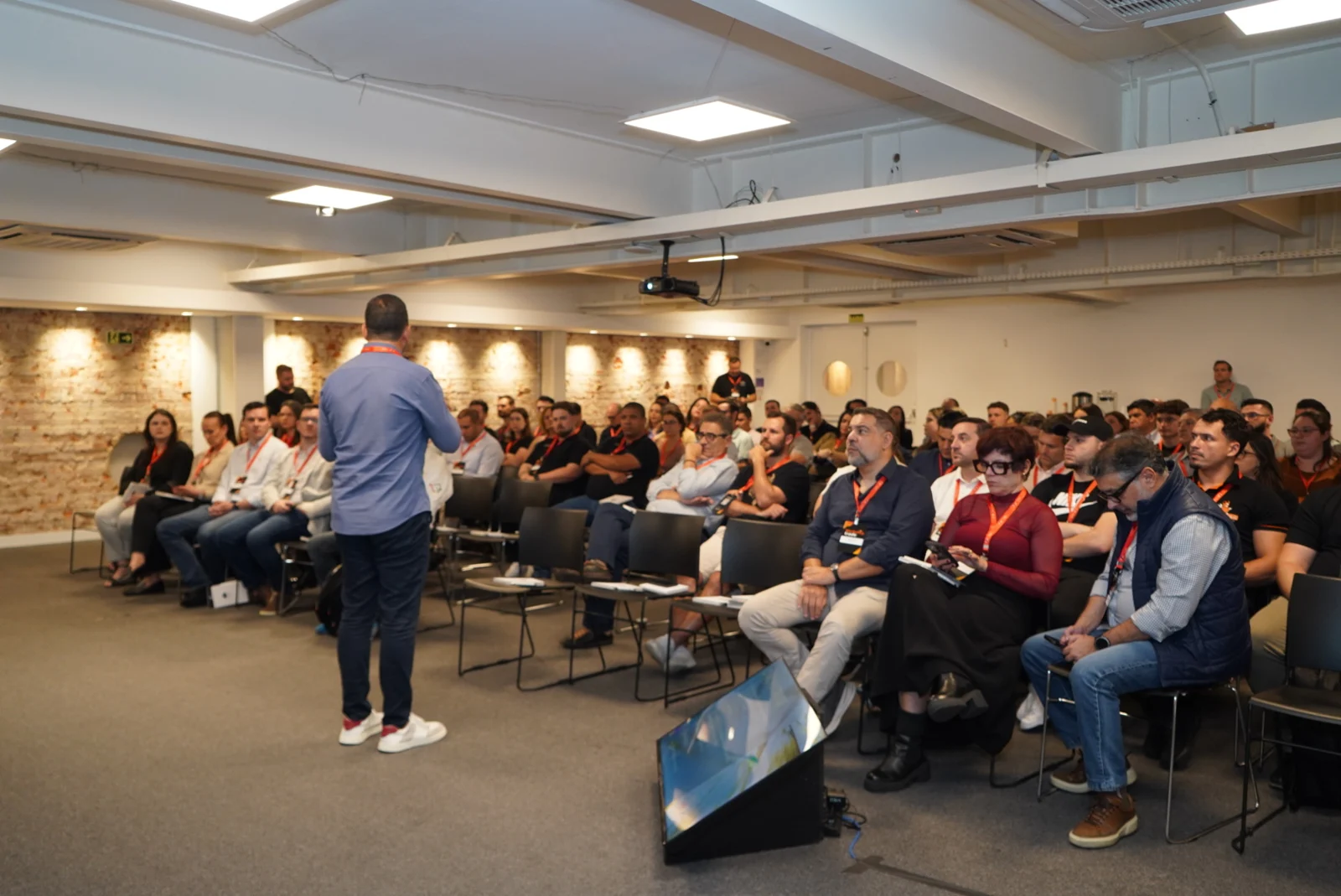 Palestrante conversa com plateia em sala de eventos