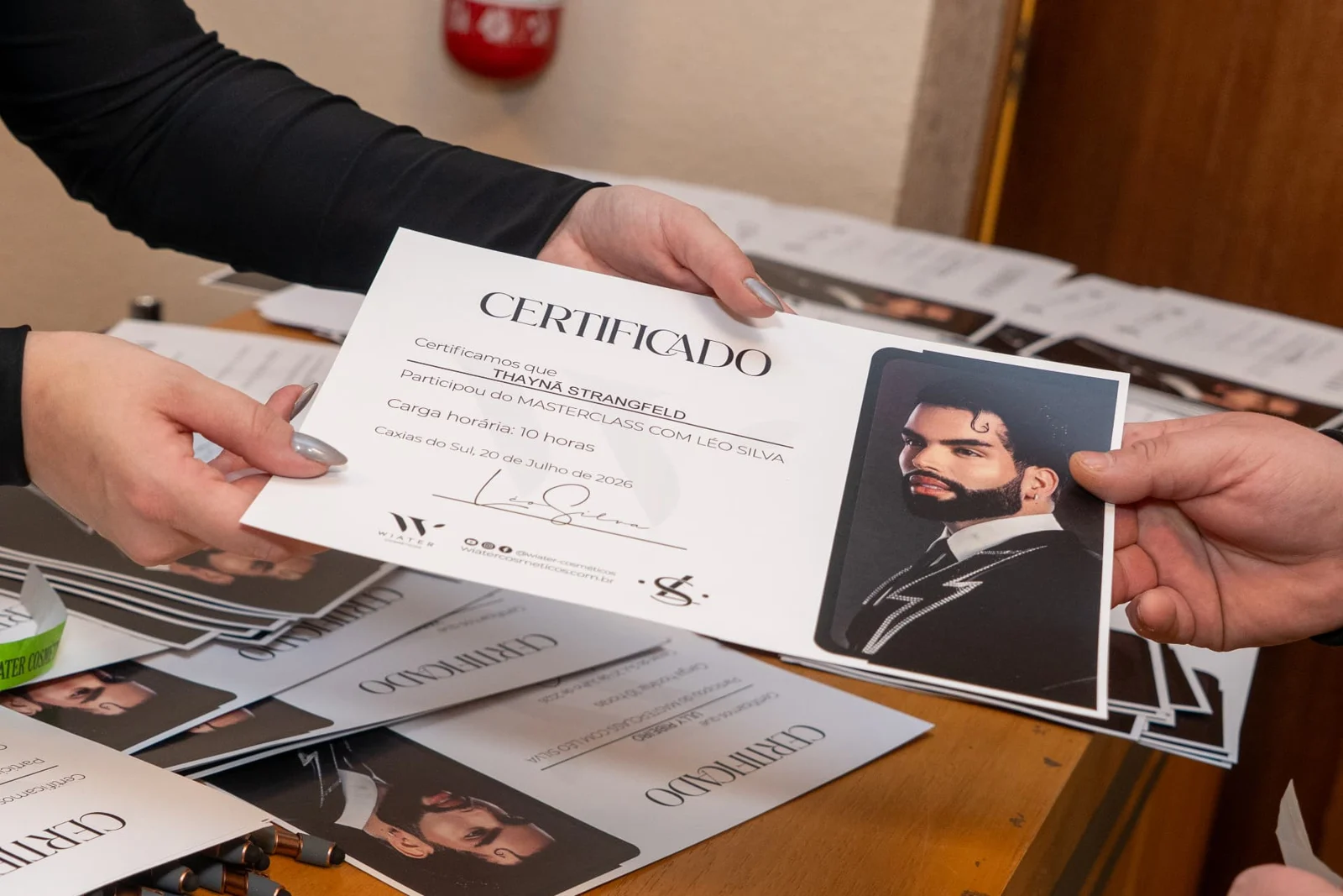 Mãos seguram certificados do evento